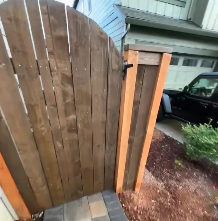 Custom cedar gate with an arched top set between the house and garage