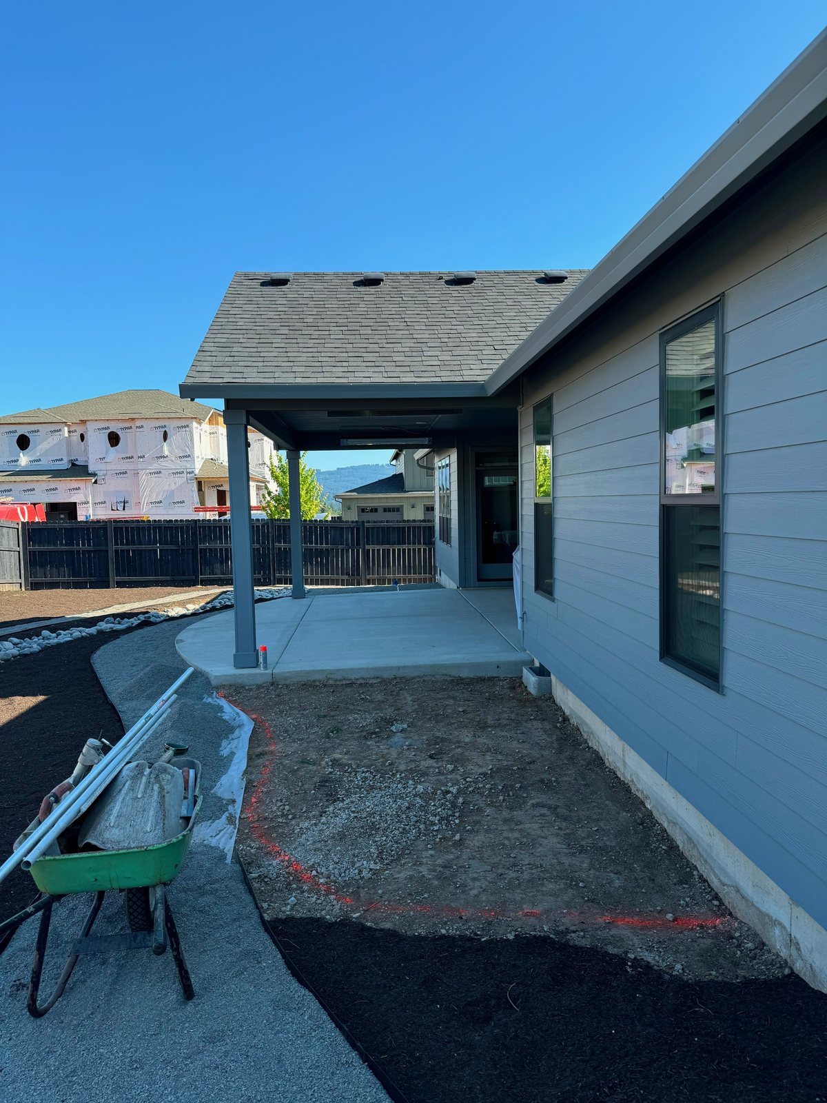 Curved patio area staked and marked with layout paint beside a new home's covered porch
