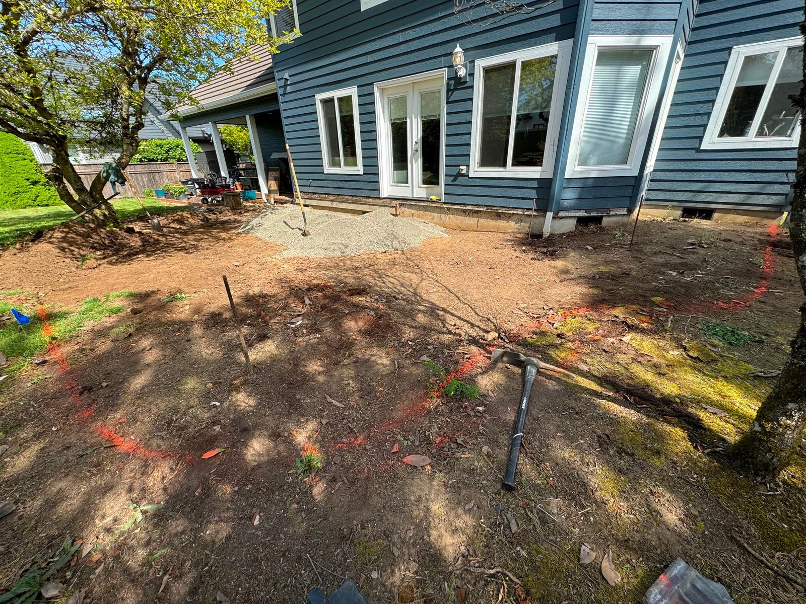 Backyard marked out with orange layout paint before the stamped concrete patio was poured