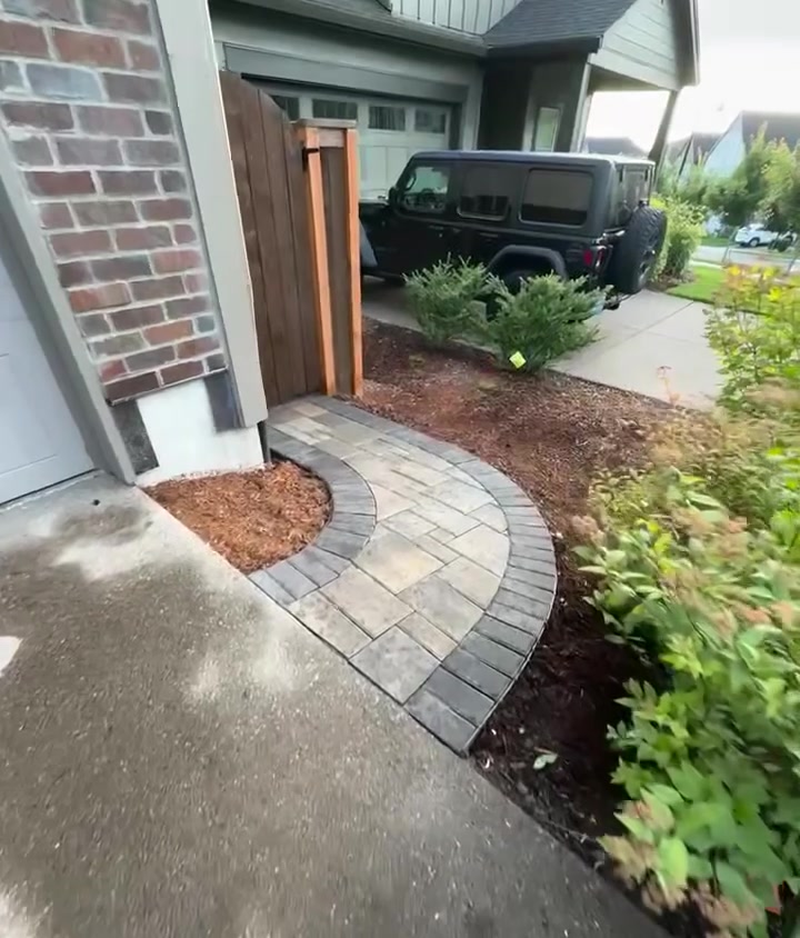 Curved paver walkway leading from the front entry, edged with charcoal border pavers and bark mulch